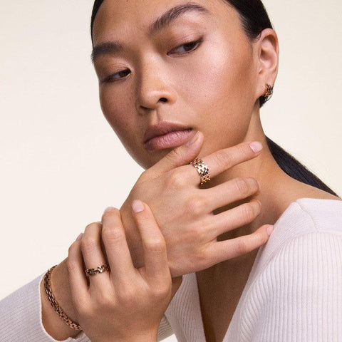Elegant Daniel Wellington 5-link ring in PVD-plated rose gold stainless steel worn on a model's finger.