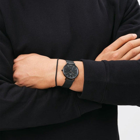 Sleek black Daniel Wellington Ashfield stainless steel mesh bracelet paired with a matching black mesh watch.