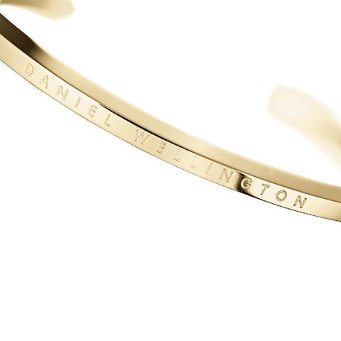 Minimalist Daniel Wellington gold stainless steel cuff bracelet featuring elegant engraved branding.