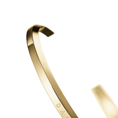 Minimalist Daniel Wellington gold stainless steel cuff bracelet with elegant engraved branding.
