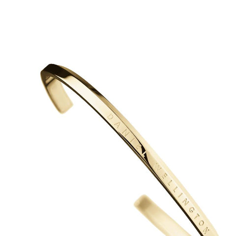 Minimalist Daniel Wellington gold stainless steel cuff bracelet with engraved logo, featuring a sleek, polished finish.