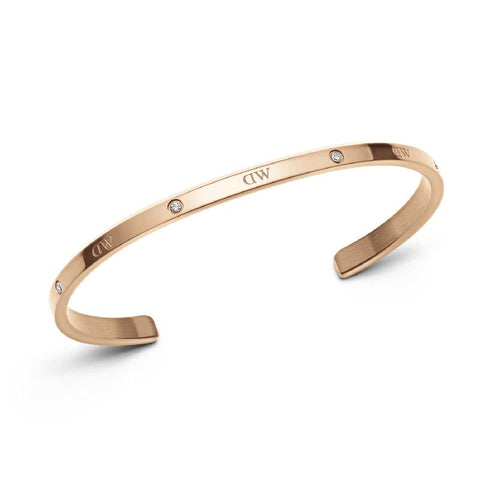Adjustable rose gold stainless steel cuff bracelet featuring six sparkling crystals and delicate Daniel Wellington branding.