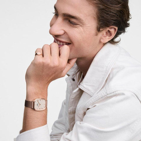 Minimalist rose gold Daniel Wellington signet ring with a sleek, curved design worn on a man's finger.