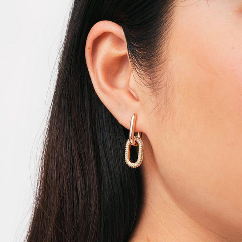 Chunky rose gold plated brass link earrings featuring refined crystal details in a claw setting worn on an ear.