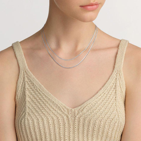 Elegant Daniel Wellington Elan flat chain necklace in polished silver stainless steel worn as a layered choker.