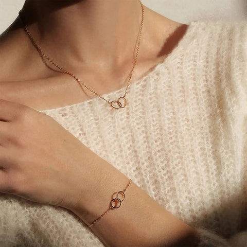 Elegant rose gold Elan Unity bracelet and matching necklace featuring delicate interlocking rings in stainless steel.