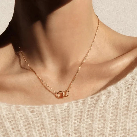 Elegant rose gold Daniel Wellington Elan Unity necklace featuring two interlocking rings on a delicate chain.
