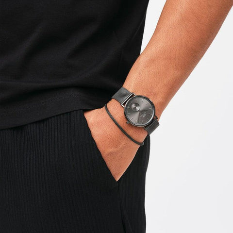 Daniel Wellington graphite stainless steel mesh bracelet paired with a matching watch on a wrist.