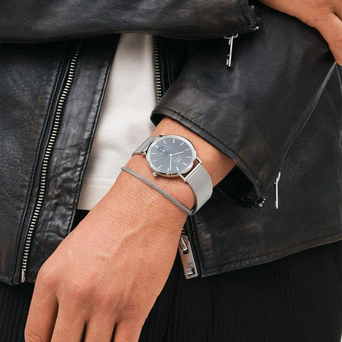 Elegant silver stainless steel mesh bracelet paired with a matching Daniel Wellington watch on a wrist.