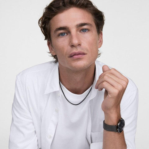 Man wearing a sleek graphite stainless steel Daniel Wellington Tide mesh necklace with a matching mesh watch.